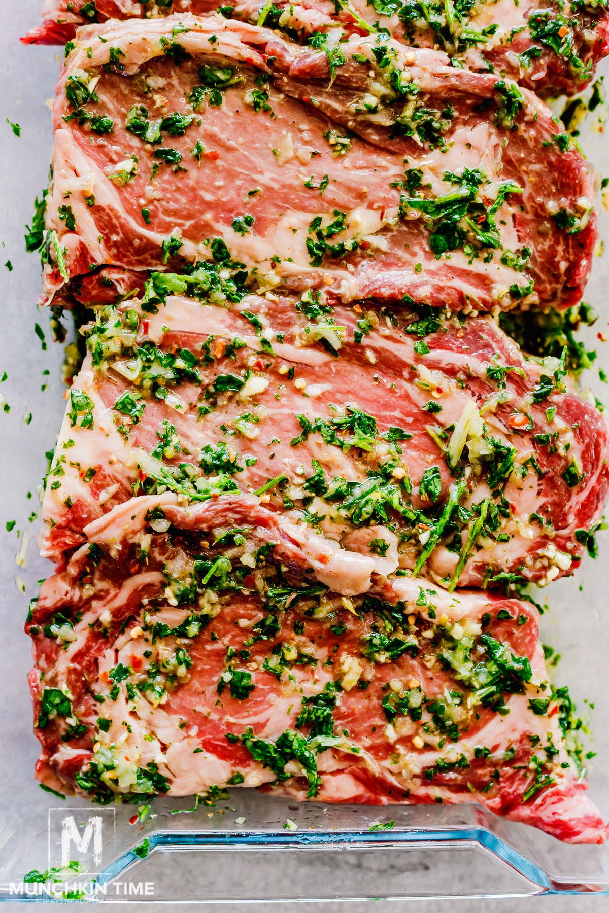 ribeye steak marinating in a glass container.