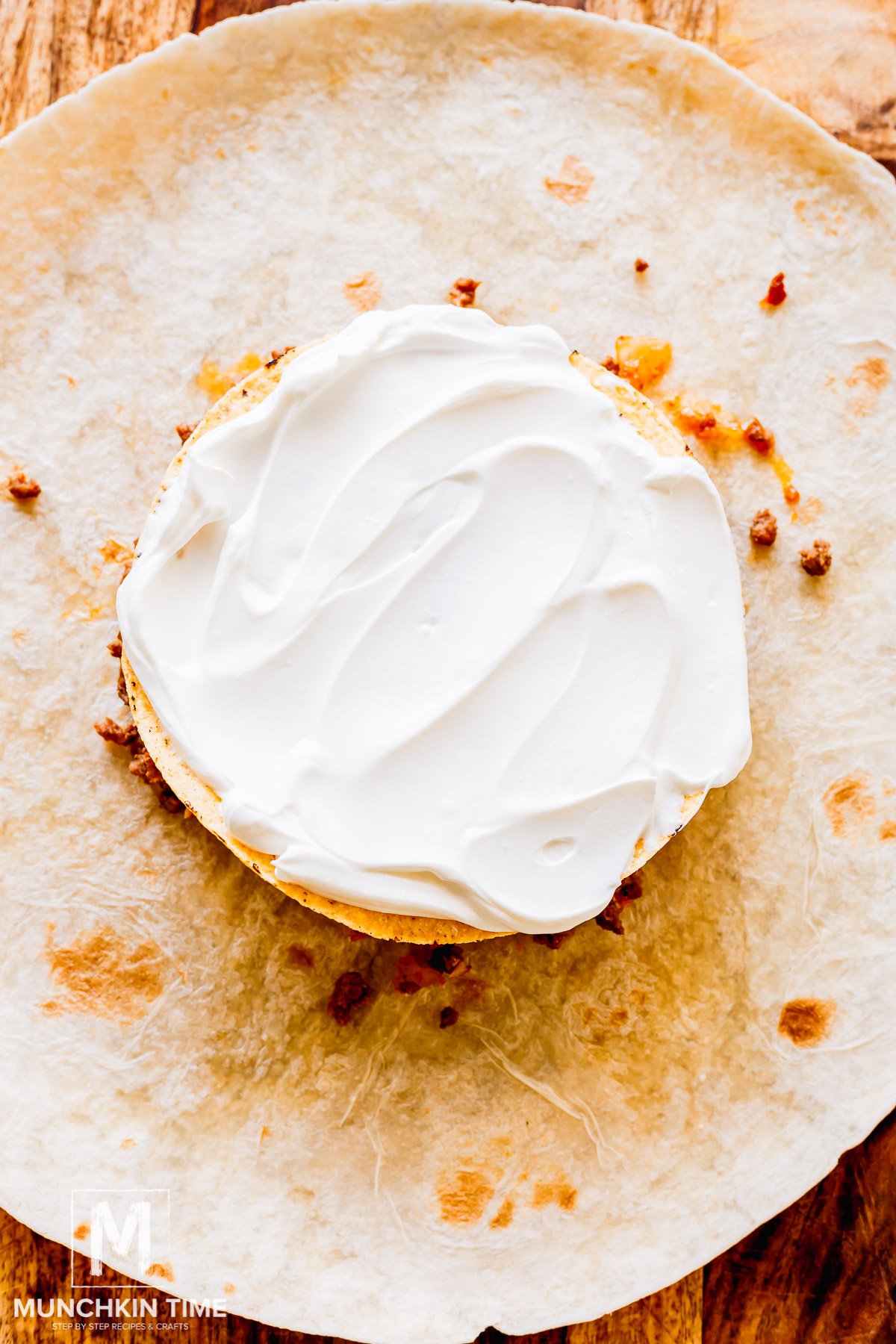 tostada added over the meat with melted cheese and sour cream spread over the top.