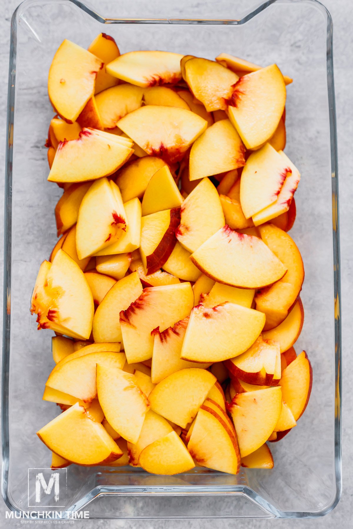 Sliced peaches placed in a casserole dish.